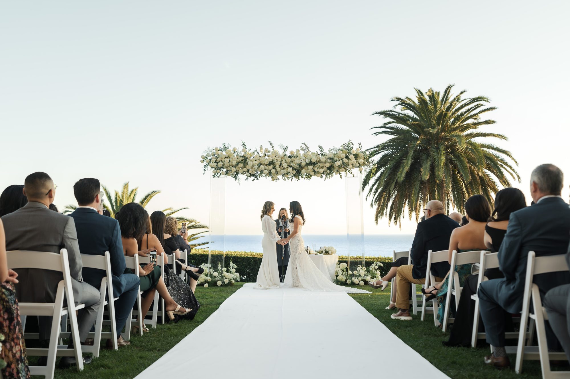 Oceanfront wedding ceremony arch framed by palms