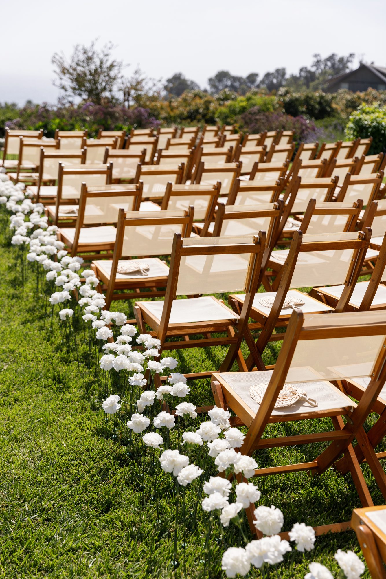 Ceremony aisle lined with white blooms and wood chairs